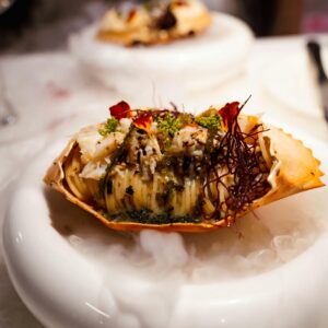 Delicious gourmet crab dish garnished and served on an elegant platter with a smoky mist.